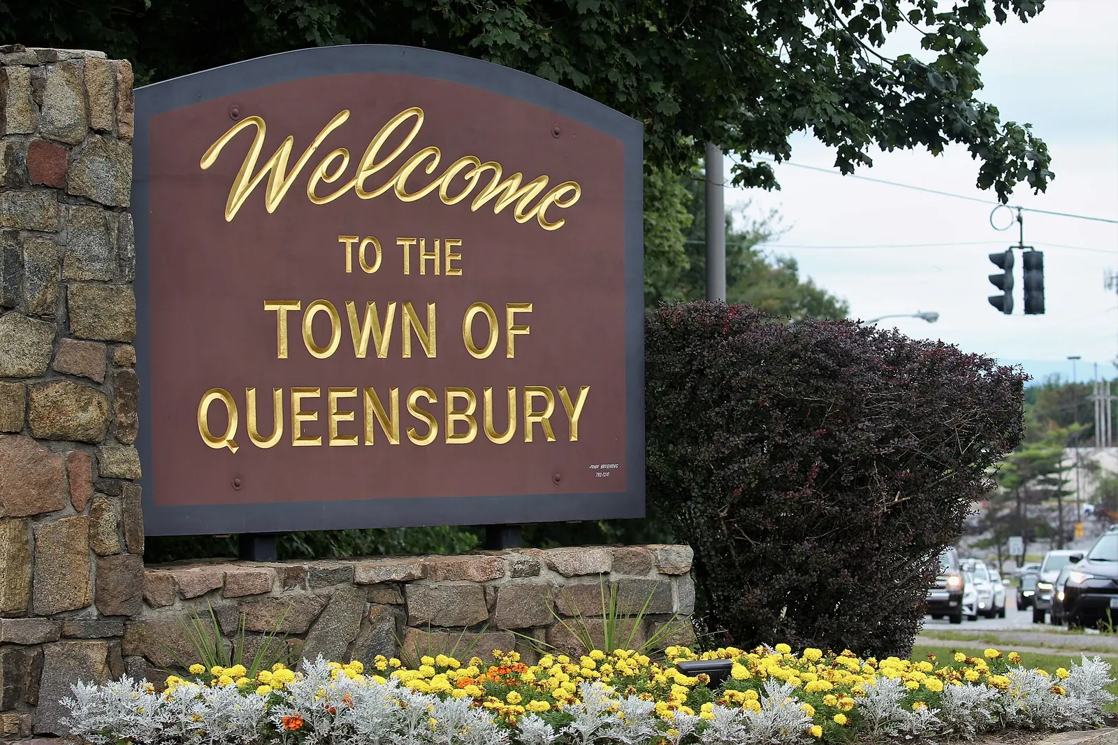 Welcome to the Town of Queensbury sign on a stone base with flowers